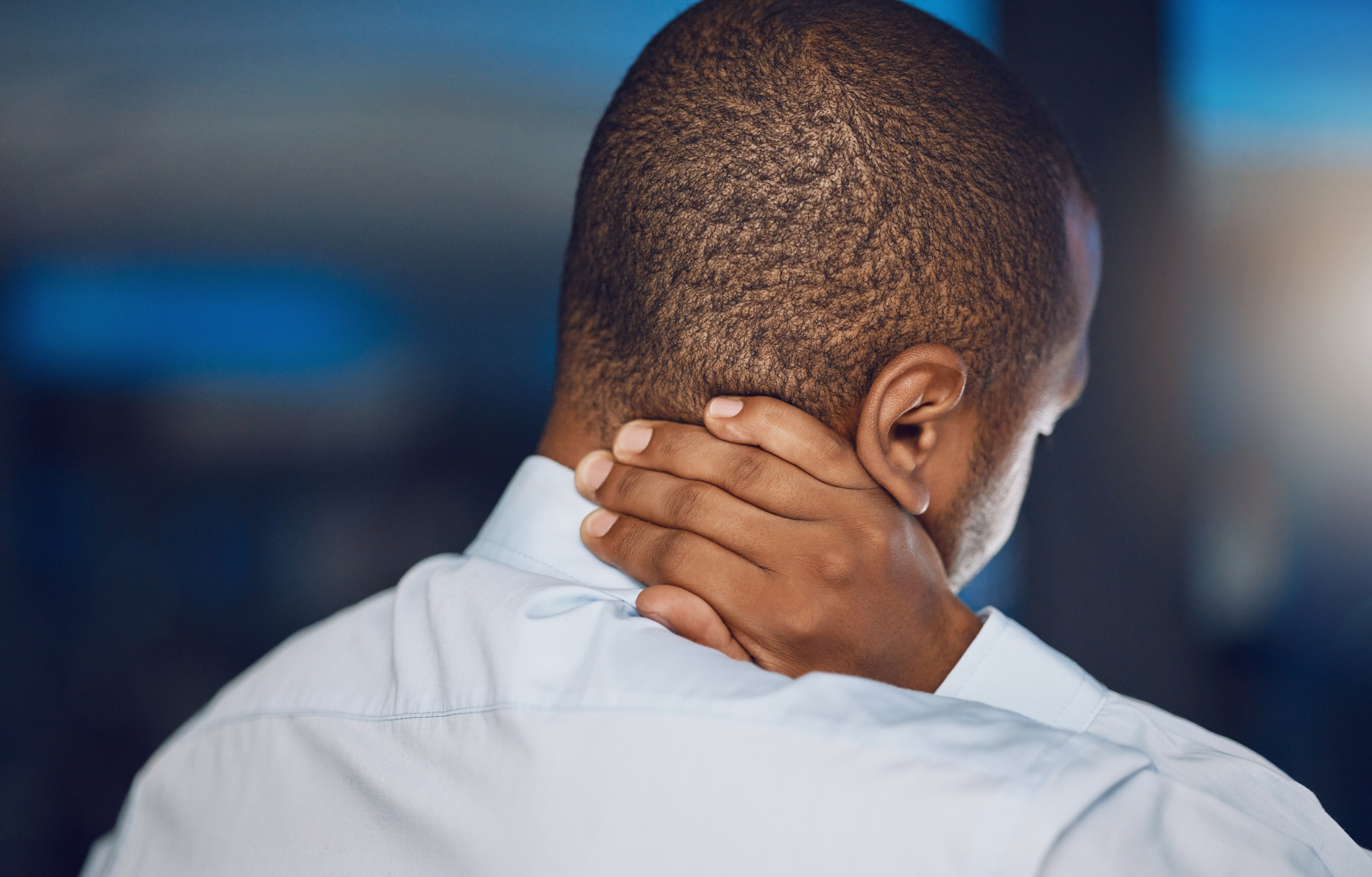 Above rearview young african man holding his neck in pain. African american business man suffering .