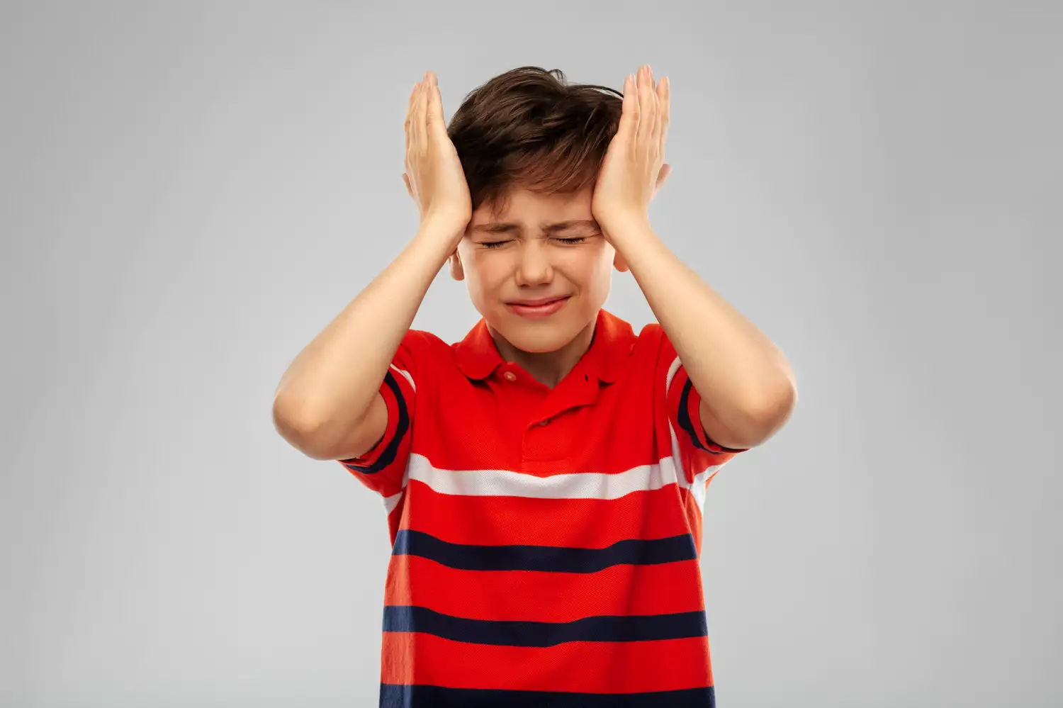 A child with a headache holding his head