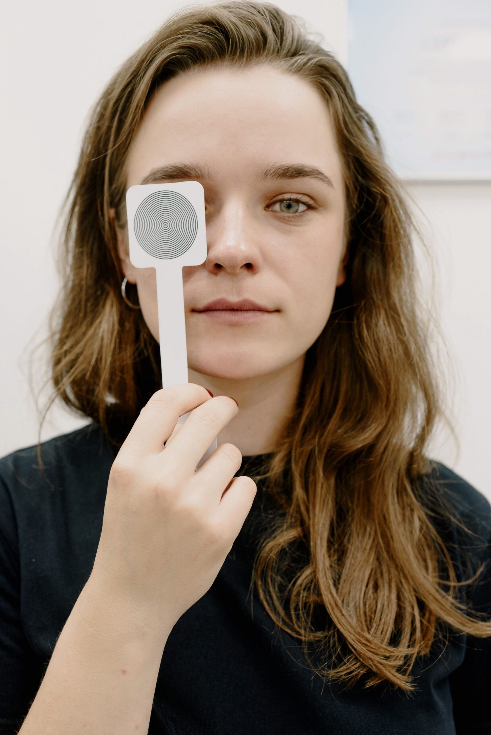 Patient undergoing binocular vision testing to evaluate eye alignment and visual instability symptoms