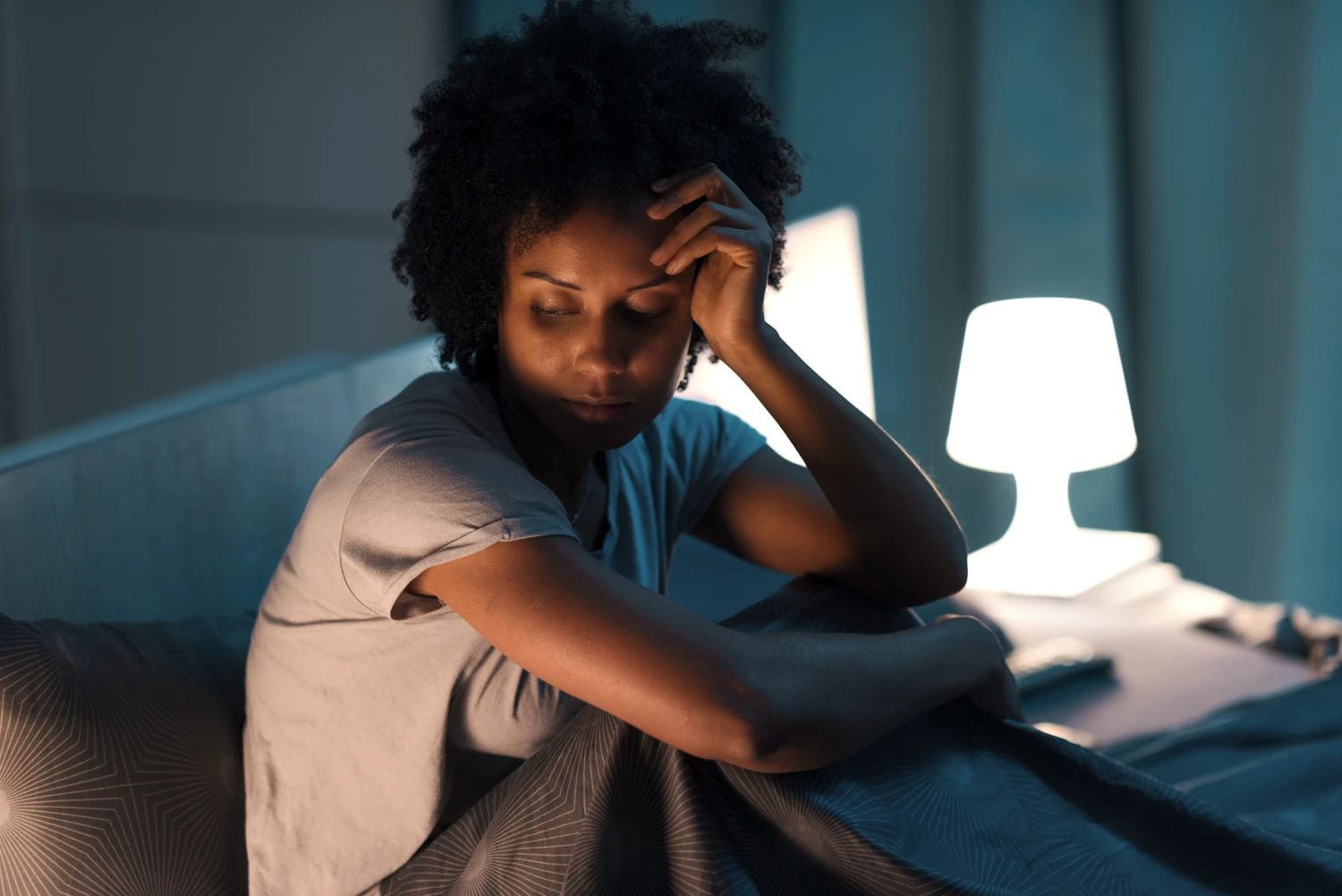 Young woman sitting in bed, stressed and worried